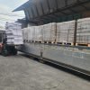 Pengiriman kemasan kaca besar di truk dengan pallet di luar gudang.
