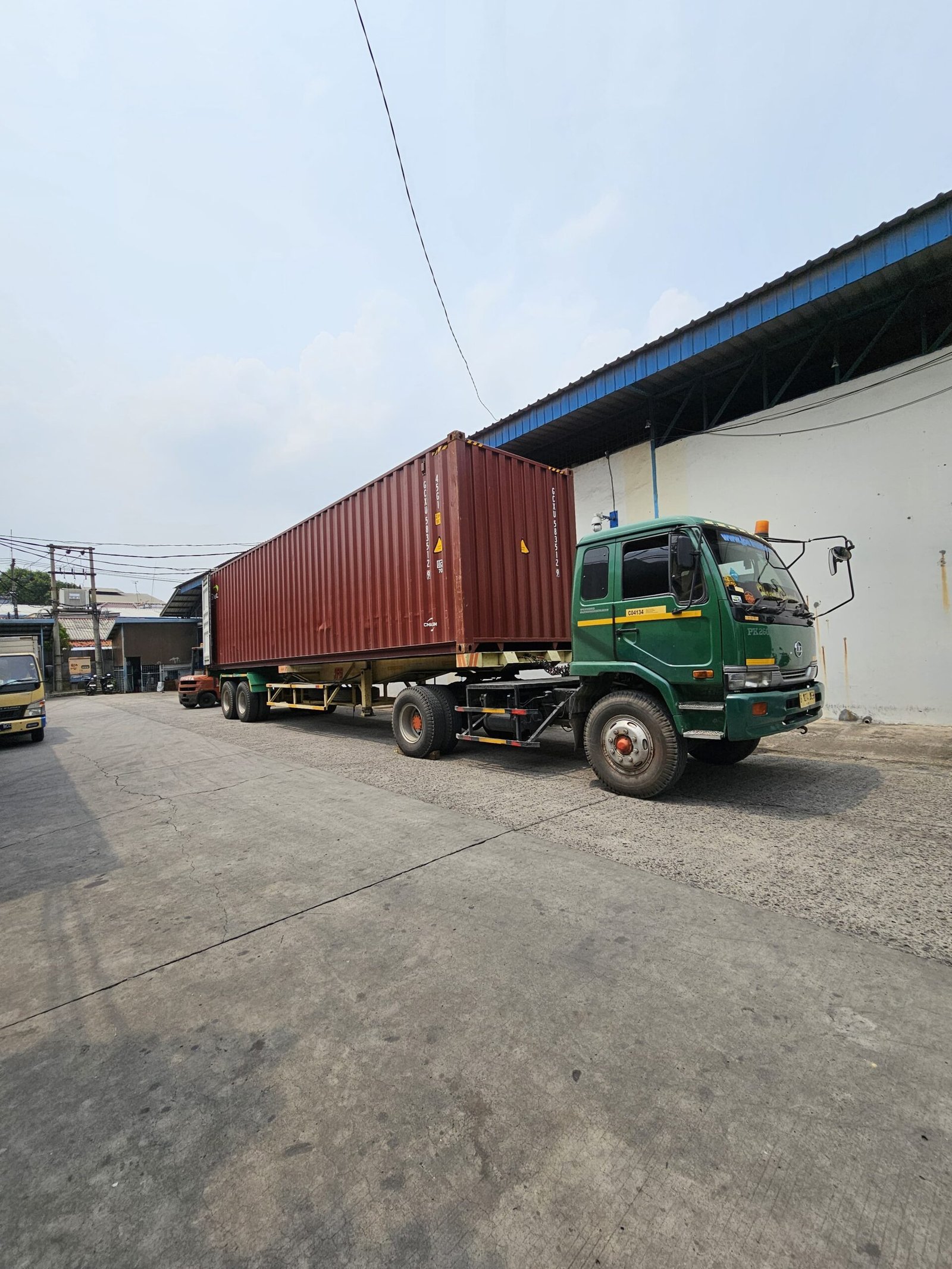 Truk pengangkut kontainer di area gudang penyimpanan.